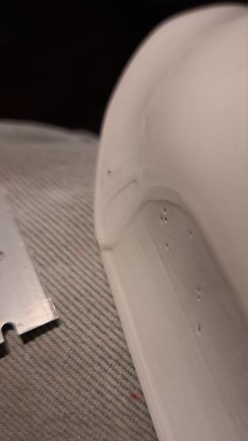 Closeup view of a painted glider part...a tailwheel fairing. The low angle of the light helps highlight runs in the not-very-good paint job. 

A straight edge razor can be used to scrape away the high parts of runs and drips, and if you're careful, you don't mar the rest of the painted surface.