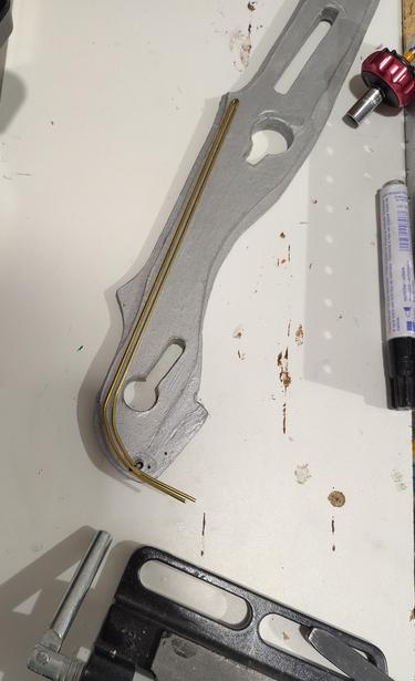 Silver painted wooden lower end of a fantasy sword with brass metal part on it, on a workbench
