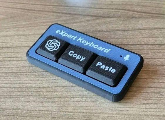 A, small, toy keyboard that contains three keys on which logo of ChatGPT, the word "copy" and the word "paste" are printed. On top of them, "eXpert Keyword" is printed.