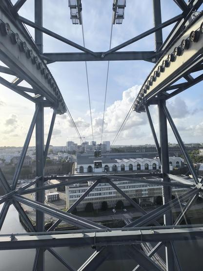 Blick aus der Seilbahn-Kabine, kurz bevor sie durch die Fachwerkstütze hindurch kommt. Rechts und links sieht man die Seilspuren und generell viele "Stangen" aus Metall.
