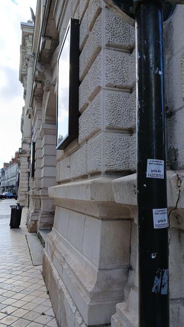 Autocollants "'La nuit du bien commun' gala de fascistes" sur un poteau devant le grand théâtre de Tours