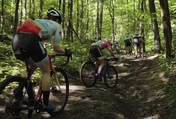 bikers going up a washed out, rocky class IV dirt road deep in the woods, some are pushing their bikes, others are still pedaling up