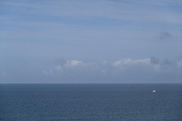 Foto auf das Meer mit Blauvariationen unter Himmel mit Blauvariationen mit blauem Fischkutter