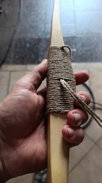 Zwischenversuch an einem Primitivbogen eine Wicklung für das Griffstück anzufertigen. Das lose Fadenende wird mittels einer Extra eingewickelten Schlaufe, nach innen gezogen