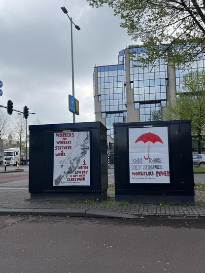 Twee bollboards op donere straat kasten met achter een spiegelgebouw, lantaarnpaal met reclame, stoplichten en een witte truck. Fietspad voor. Zie next voor omschrijving van de borden