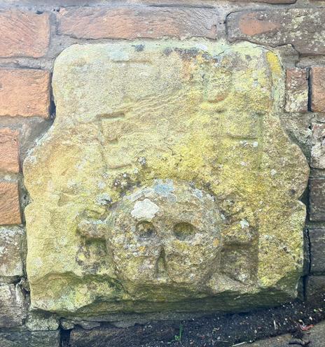 What looks like an old gravestone featuring a memento mori set into a wall in Glasgow.