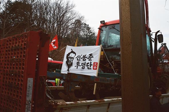 전봉준 투쟁단 현수막이 걸려있는 트랙터가 트럭 위에 고정되어 있다.