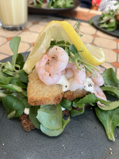 A richly topped ryebread with fried fish, shrimps, lamb lettuce, sprouts and a slice of lemon