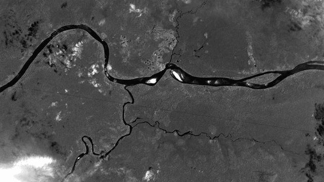 Black and white satellite image showing the Casiquiare River (flowing north to south in the center of this image), which connects the Orinoco River (running east to west) with the Rio Negro.