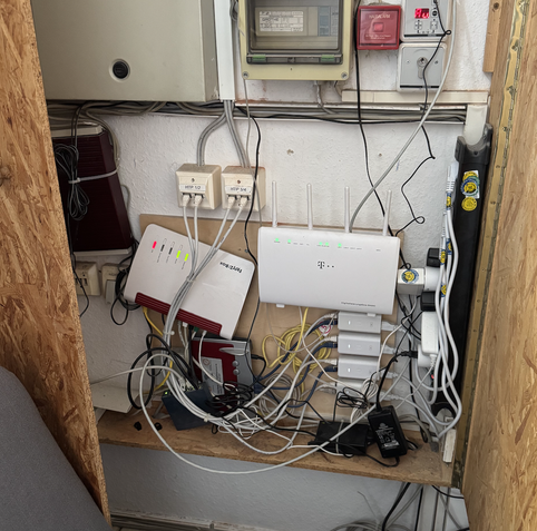 Ein Bretterverschlag mit Kommunikationstechnik: DSL-Modems, Switche, PoE-Injektoren etc.