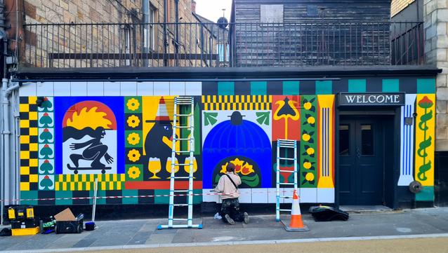 A new mural being painted on the side of a Glasgow pub.