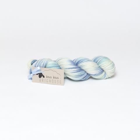 Picture shows a skein of yarn in shades of blue, green and white.