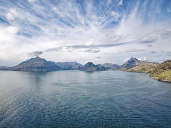 An image of a mountain range in the distance above the sea on a bright day. Isle of Skye, Scotland