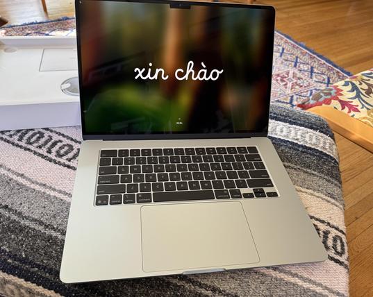 A freshly unboxed sky blue 15-inch Macbook Air with the Vietnamese greeting, “xin chào” in a large script-like font across the screen. The white box it was shipped in is behind it.