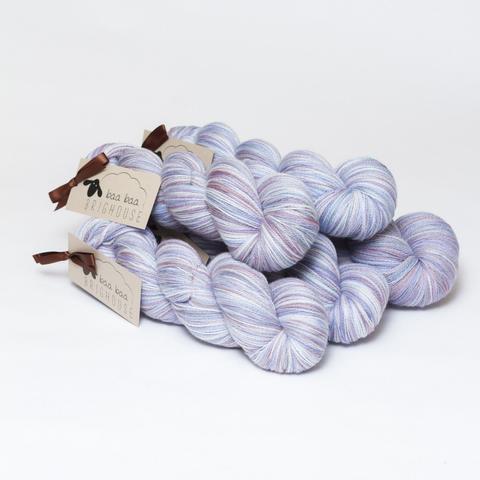 Picture shows a pyramid of five skeins of yarn positioned diagonally in shades of purple, blue, white and pink.