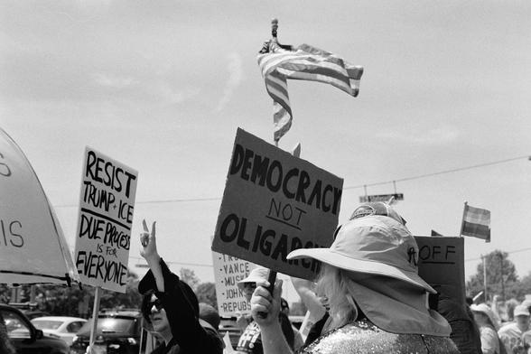 A “democracy not oligarchy” sign with a flag waving above
