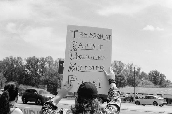 A sign spelling out the words “treasonist, rapist, unqualified, molester, puppet”