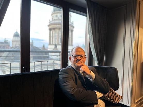 Sven Oliver Rüsche sitzt vor Berliner Skyline im Capital Business Club.