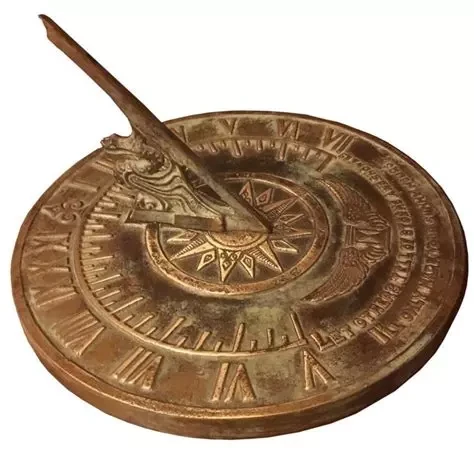 Photograph of a golden sundial against a white background.