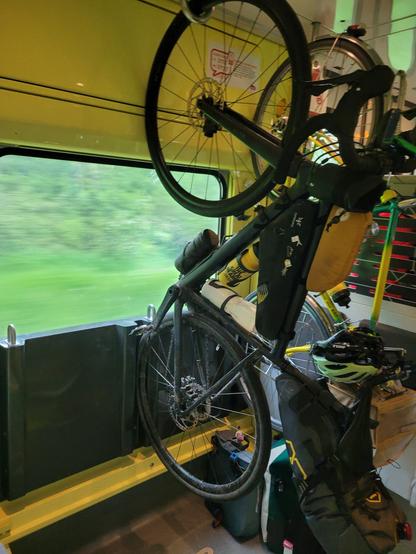 Mon vélo gravel noir équipé de sacoches en bikepacking suspendu à un anneau dans le wagon vélos d'un train