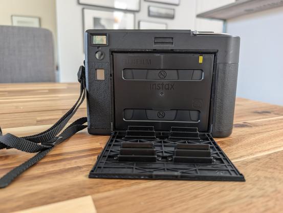 An Instantkon Instax camera with the back open showing a recently load pack of film.