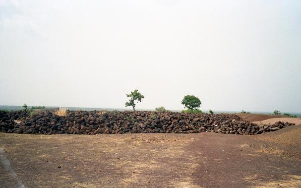 Dirt, a wall, two trees, sky.