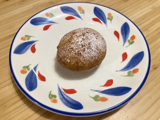 A small round doughnut dusted with powdered sugar.