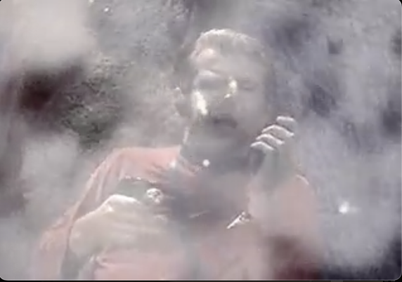 A Starfleet lieutenant is being slowly choked by a sparkly, whiteish blurry cloud as he speaks into his communicator in the Star Trek: Original Series episode "Obsession".