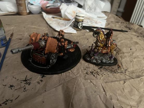 Warhammer 40K Miniatures. 

Artillery team, black uniforms with orange helmets, gloves, and boots. Orange blast shield on the siege gun. 

Lord Marshall on a clawed, yellow horse-like creature with purple mane and purple forelimbs. Also wearing black and orange uniform.