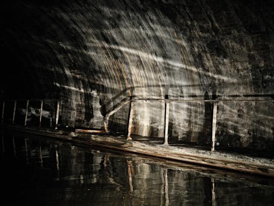 Light shining on the water and reflecting on the walls of a tunel.