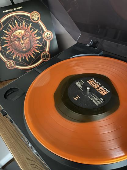 Employed To Serve album Fallen Star orange and black vinyl on turntable with album cover on the left.