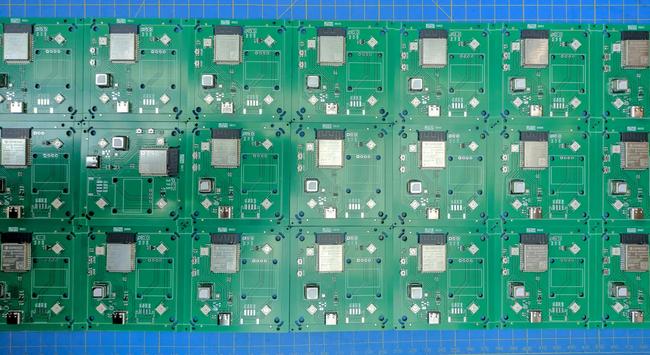 A number of small square pcbs arranged in a 8x3 pattern on a blue cutting mat. Each board has a esp32-s3 module, scd4x co2 sensors in a small metal case, 4 neopixel leds, a usb c connector and a bunch of smaller components. A larger display footprint is not populated. The second board from the left in the middle row is rotated 90 degrees clockwise while all others are oriented the same way.