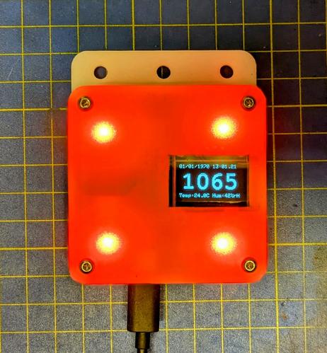 Small square plastic enclosure with 4 red lights illuminating the whole front panel through a diffusor film. A cut out on the right shows a small display reading 1065ppm