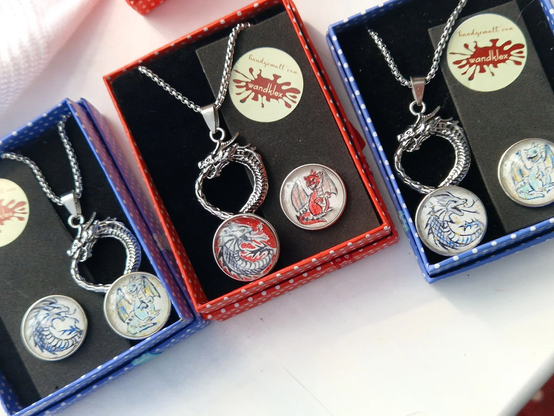 Anhänger aus Metall in Form eines stilisierten Drachenkopfes mit handgemalten 20mm-Druckknopfmotiven (wechselbar) mit Drachenmotiven