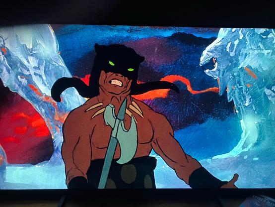 A crazy berserker guy from Fire and Ice. Has an axe in hand a sort of leopard cowl. Behind him is white ice and also striking warm colours beyond that.