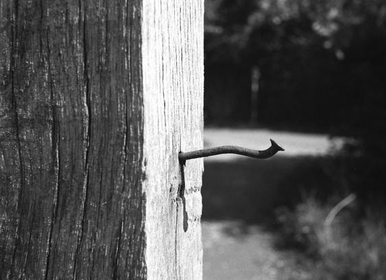 Ein verbogener Nagel in einem Holzpfeiler