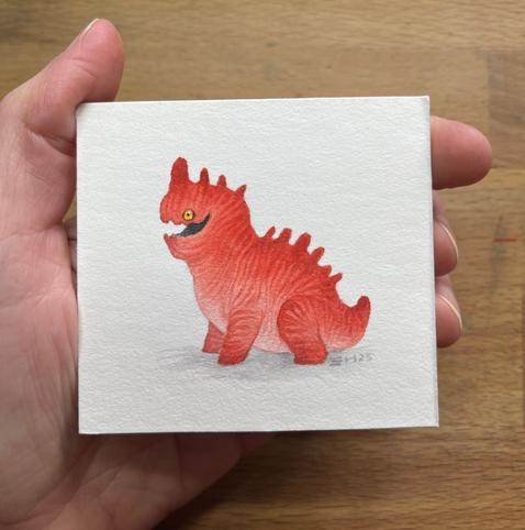a small red dragon with a yellow eye facing left. It has a pink tummy and is red all over with darker red stripes.