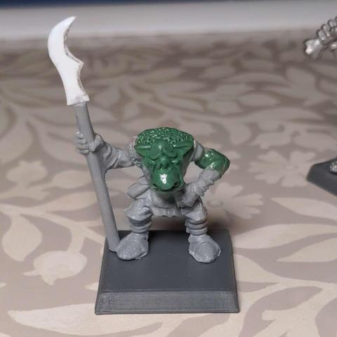 An in progress shot of a plastic model orc with various areas re-sculpted in epoxy putty with a sad face