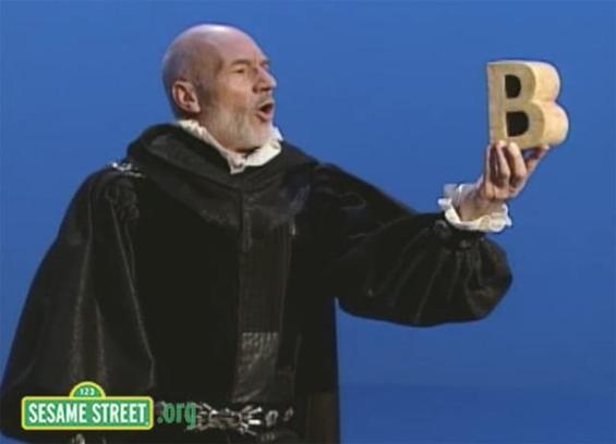 Patrick Stewart in a Shakespearean outfit holding the letter 'b'