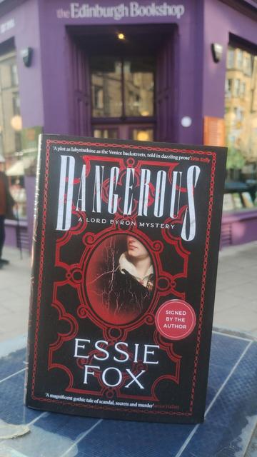 Cover of Dangerous by Essie Fox, black and red cover with a partial portrait of Lord Byron, outside the Edinburgh Bookshop