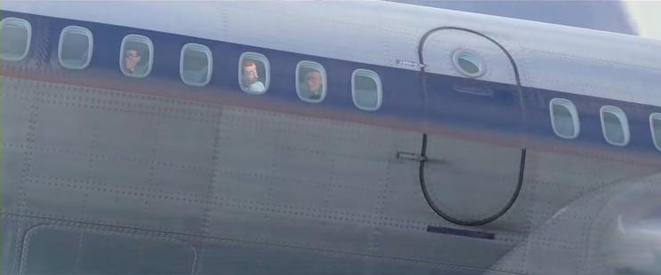 The aftermath of a superhero getting sucked into a jet turbine, which happens offscreen. It shows people in a plane looking out of the windows, worried.