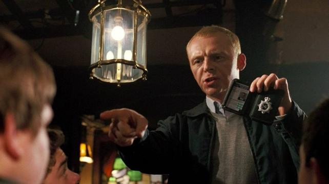 In a pub, an off-duty British police officer holds up his badge and pointing at someone as he demands to know their date of birth