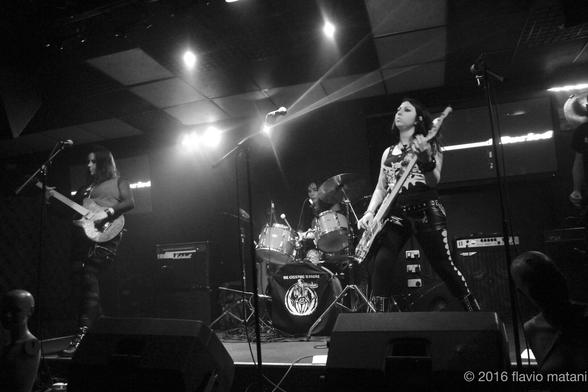 A punk band in concert; at the centre the front-person and bass player of the band, Consuelo. Black and white.