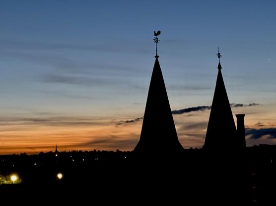 Sun has just set; the towers of the local church in contrast to the orange and blue sky.