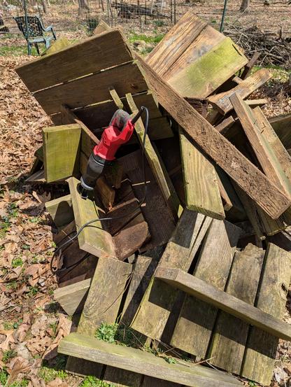 A large pile of decking, not cut into smaller, manageable pieces. On the pile is a red Craftsman Sawzall.