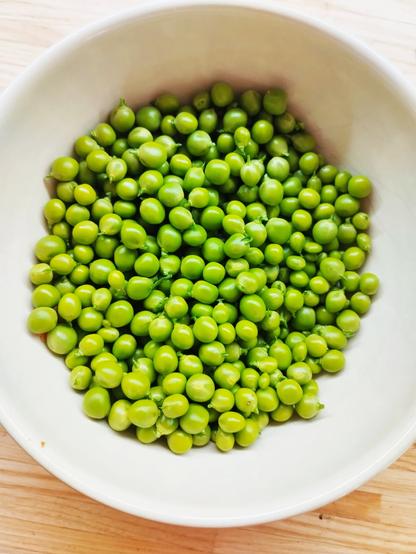 105 grammes de petits pois frais du jardin dans un bol blanc