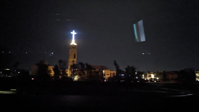 A church with an enlightened cross at the dark sky.
