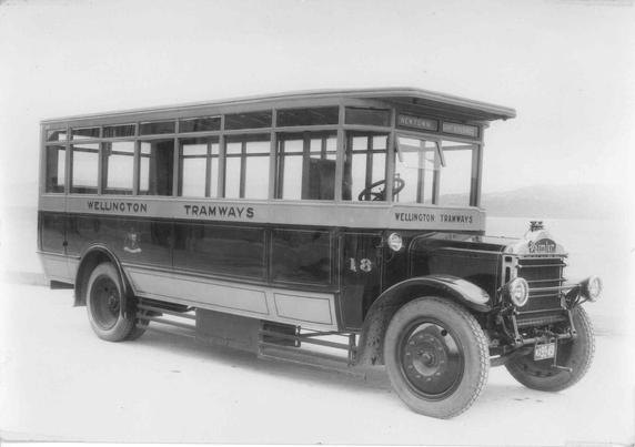 Black-and-white photo: Daimler Bus. 1927. Photographer unidentified. Description: An angled view from the front right of the bus, number 18, painted at front and the side “Wellington Tramways”. At the front the route is given as “Newtown” and “Govt Buildings”. Citation: Wellington City Council Archives, 00699-30. https://archivesonline.wcc.govt.nz/nodes/view/155659