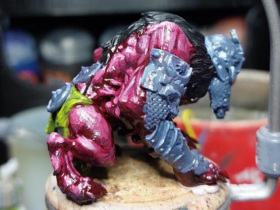 Haunched creature with skin that looks flayed rather than natural. It's wearing a helmet, arm armour, has a long mane and a green loincloth. It's all a bit gross