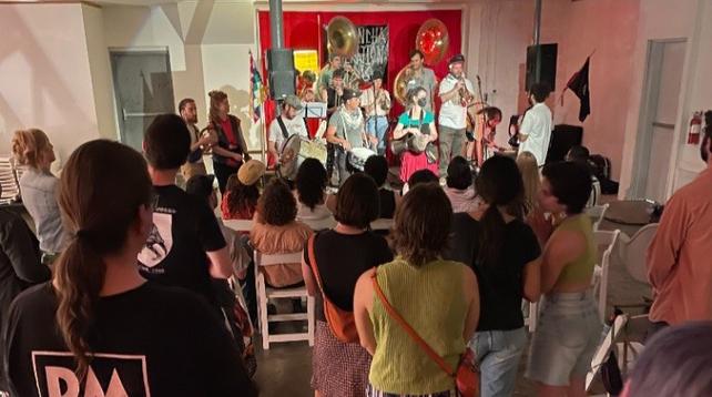 A photo from the back of the audience towards a stage full of musicians playing.